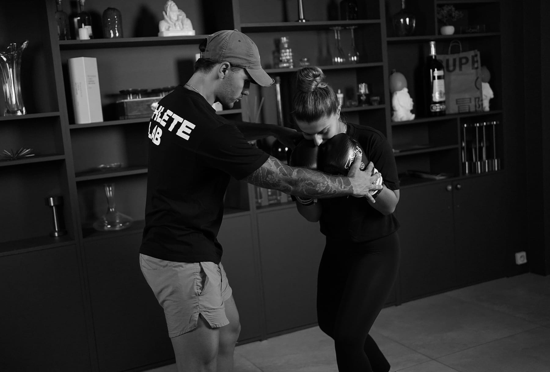 Coach corrigeant la position d'une cliente avant une frappe de boxe